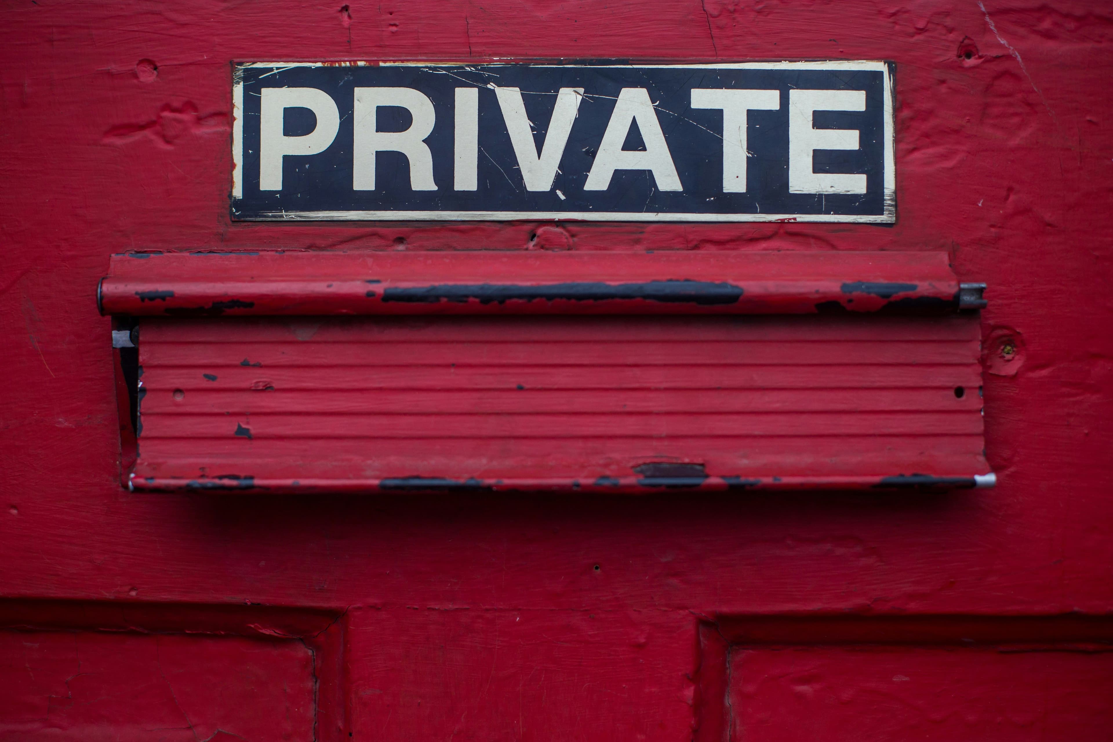Rote Tür mit Briefschlitz und einem Schild mit der Aufschrift „PRIVATE“.
